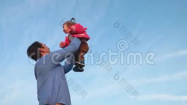 幸福家庭的观念.. 爸爸把婴儿高高地抛向天空。 爸爸和他的小女儿在公园里玩。 爸爸扔了